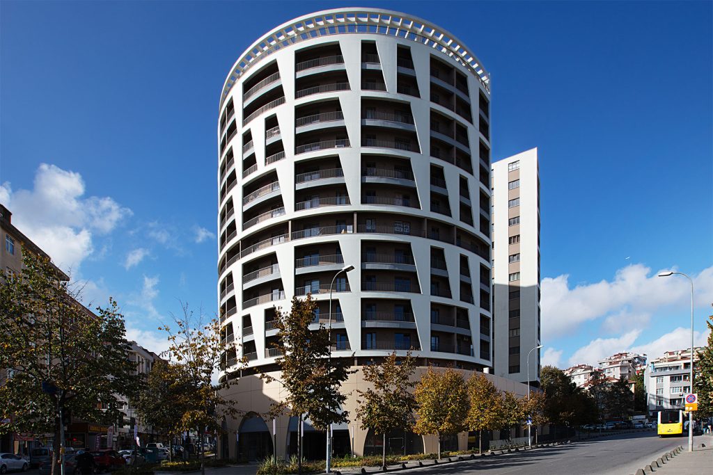 Denge Towers'ın silindirik beyaz bantlı cephesi, cadde tarafından görünüm